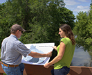 Two scientists reviewing a map in front of Beaver Creek.