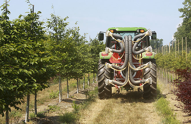 Tractor with new variable sprayer applying pesticides at a nursery.