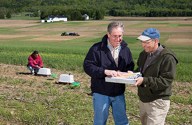 Scientists collect runoff samples and review plot layouts in a field