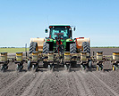 Tractor plants cotton and applies fungicide to field