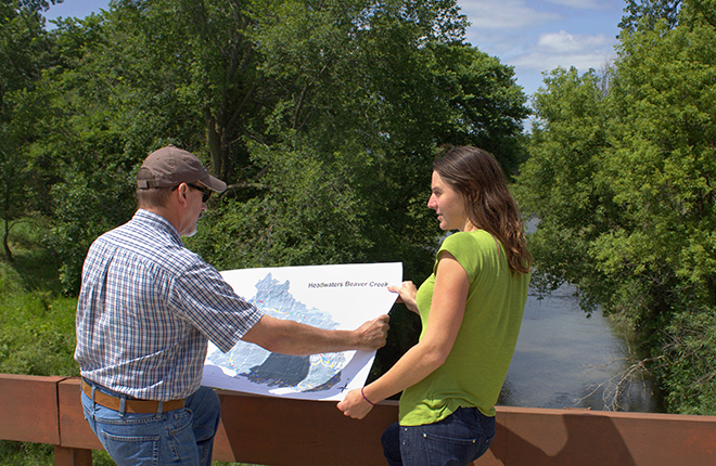 Two scientists reviewing a map in front of Beaver Creek.