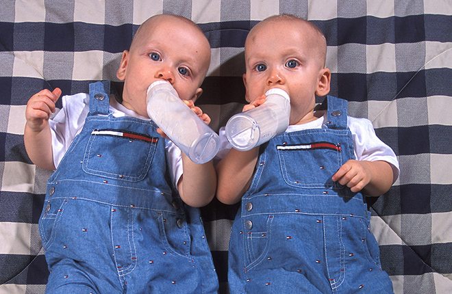 Twin boys drink bottles of infant formula.